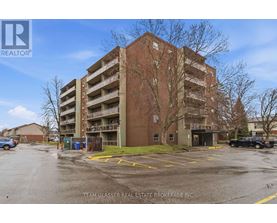 A large brick apartment building with a parking lot in front.