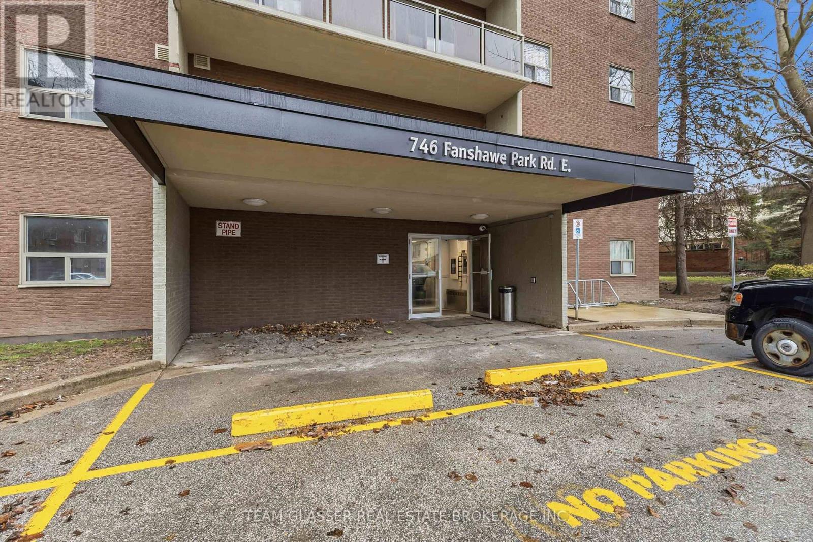 The entrance to a building with a "NO PARKING" sign painted on the pavement.