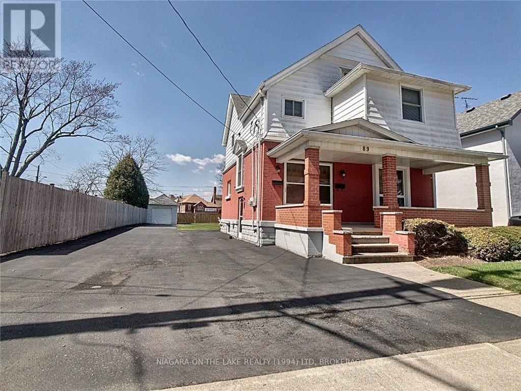 A house with a red front porch and a white garage door is for sale.