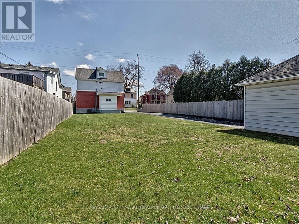 A backyard with a fence and a house in the background.