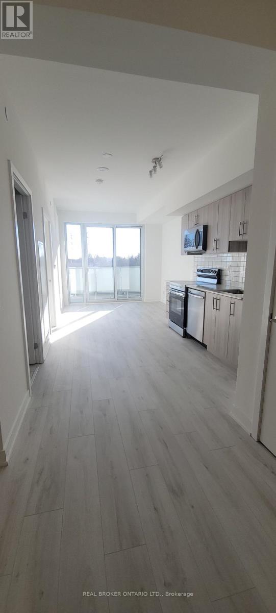 A spacious room with wooden flooring and a large window.