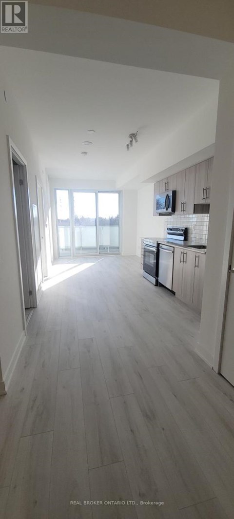 A spacious room with wooden flooring and a large window.