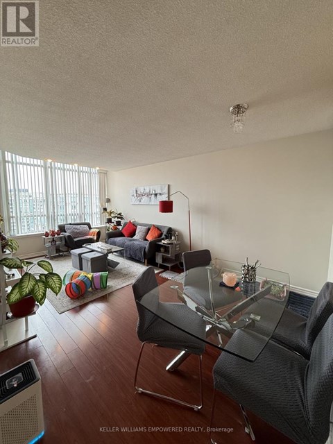A living room with a glass table and a couch with a striped throw pillow.