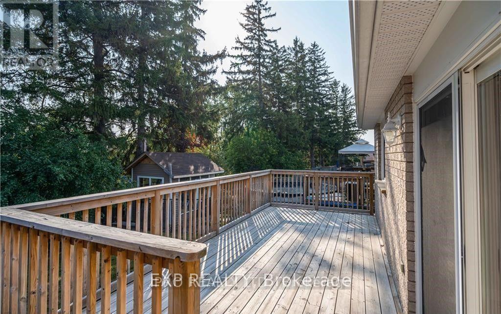A wooden deck with a railing and a view of trees and a house.