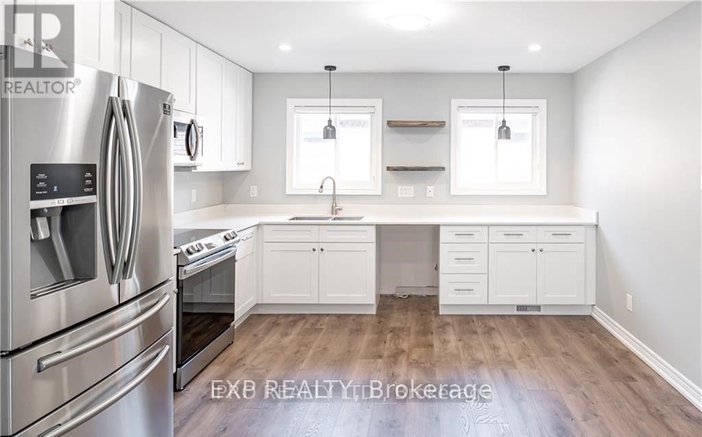 A modern kitchen with white cabinets and a stainless steel refrigerator.