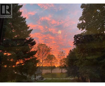A beautiful sunset with a house and trees in the foreground.