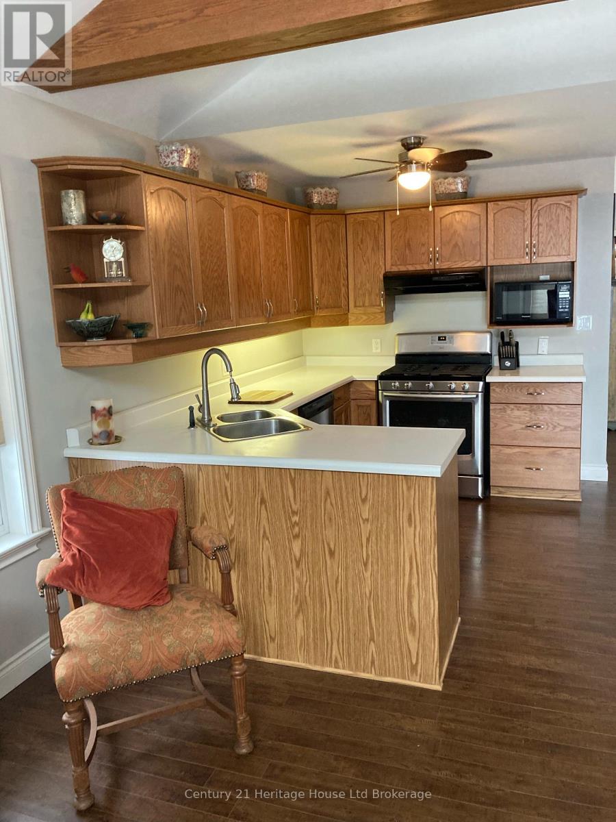 A kitchen with wooden cabinets and a chair with a red pillow.