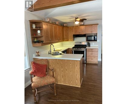 A kitchen with wooden cabinets and a chair with a red pillow.