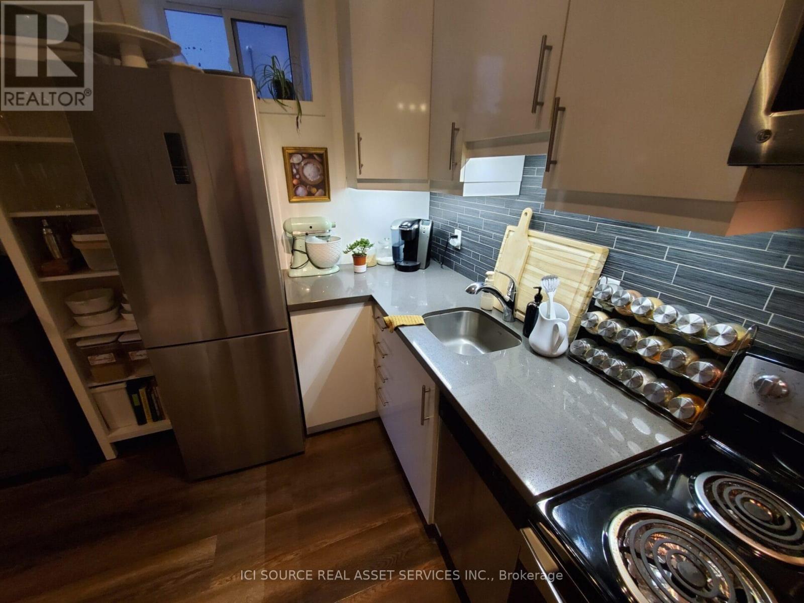 A modern kitchen with a stainless steel refrigerator and a black stove top.