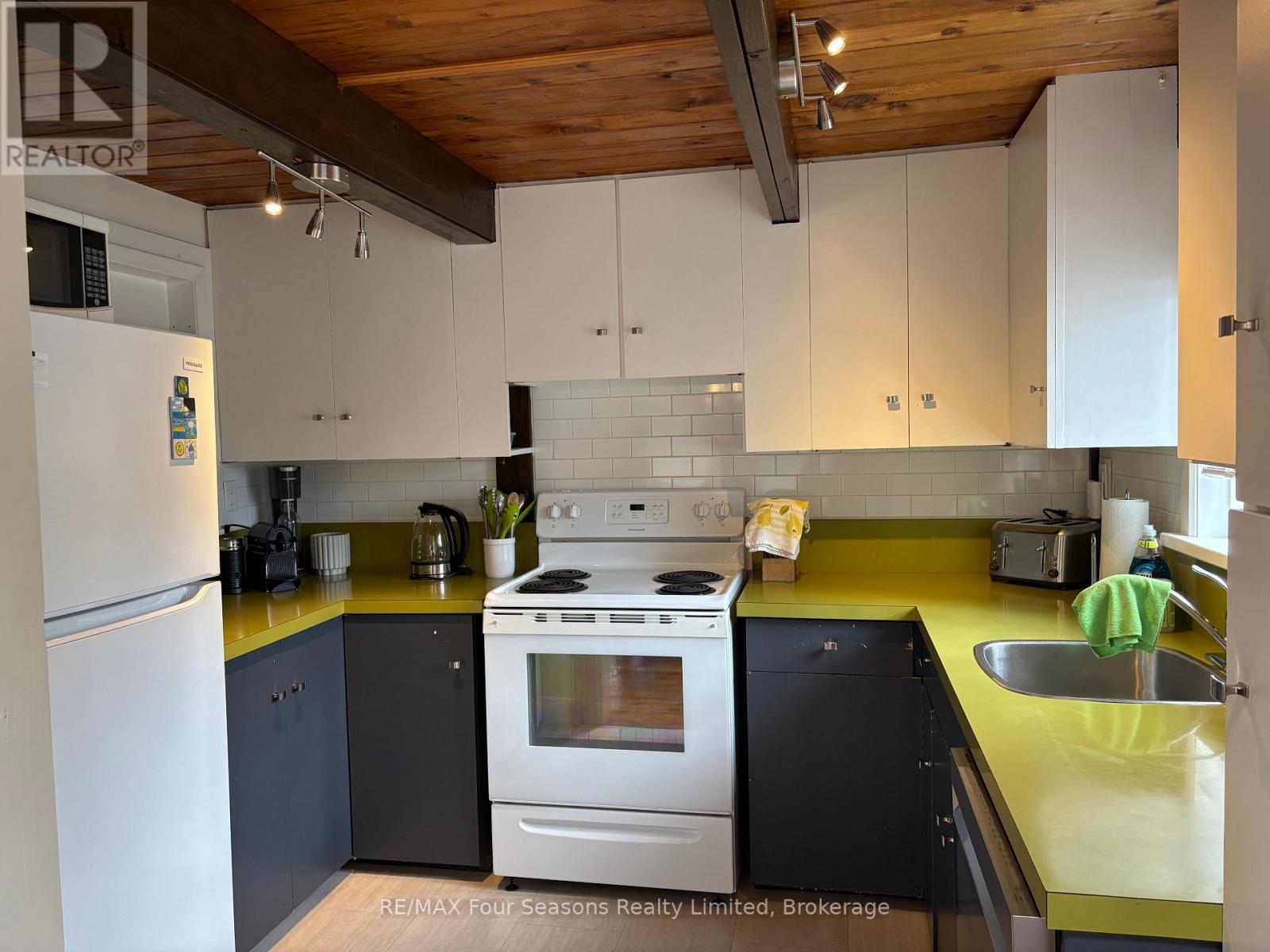 A kitchen with a white refrigerator, a white stove, and a yellow counter.