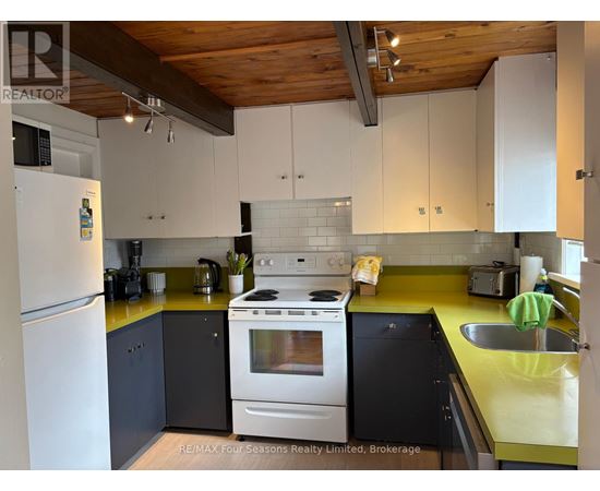 A kitchen with a white refrigerator, a white stove, and a yellow counter.