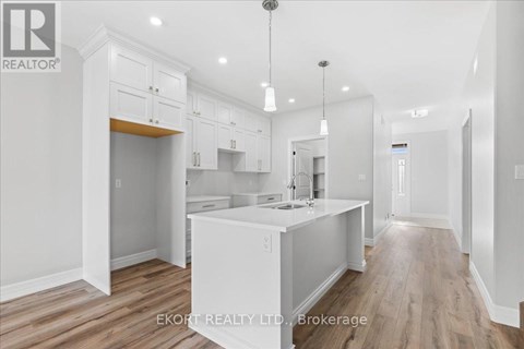 A kitchen with white cabinets and a wooden floor.
