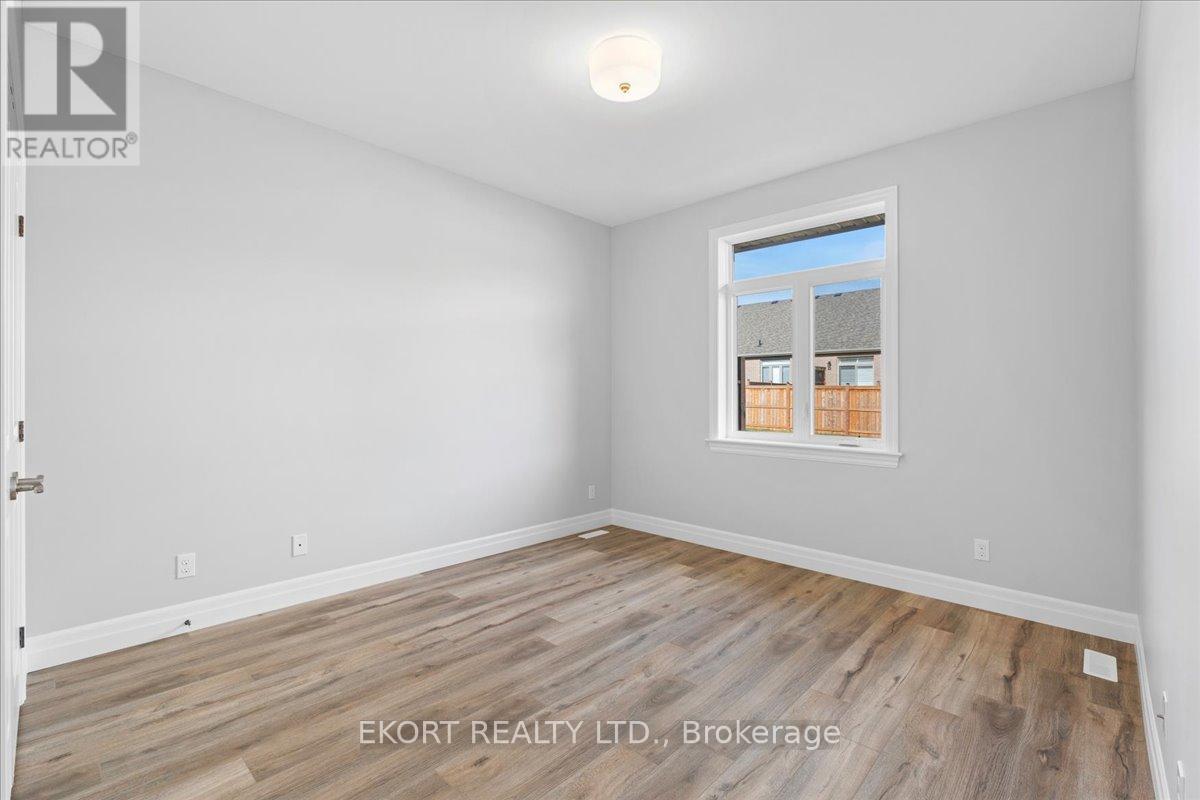 A room with wooden flooring and a window showing a view of other buildings.