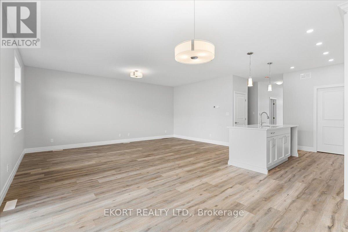 A spacious room with wooden flooring and white walls, with a cabinet and a hanging light fixture.