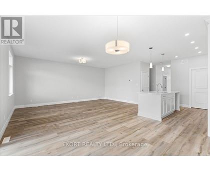 A spacious room with wooden flooring and white walls, with a cabinet and a hanging light fixture.