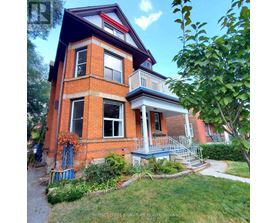A red brick house with a balcony and a small garden in front.