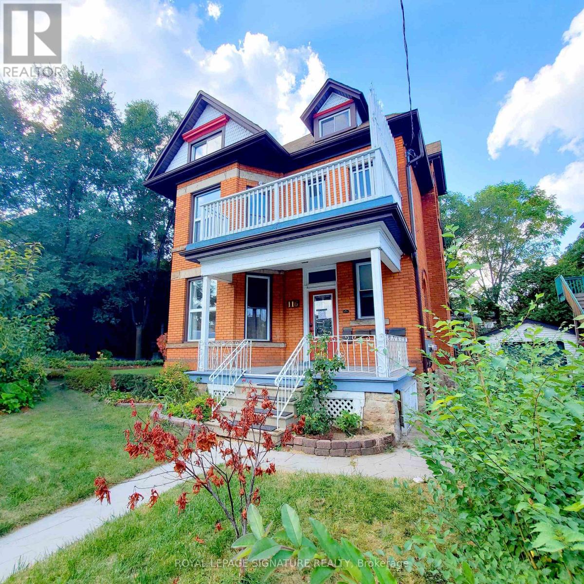 A red brick house with a white porch.