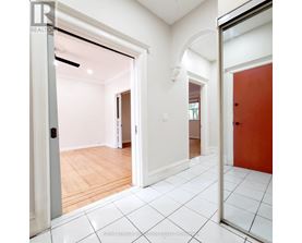 A white hallway with a red door and a white tiled floor.