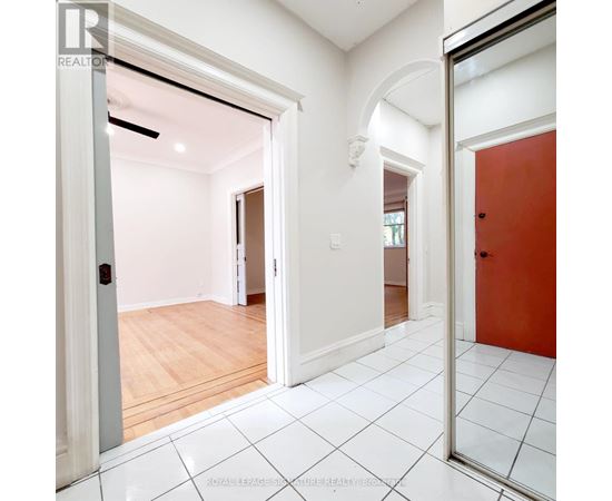 A white hallway with a red door and a white tiled floor.