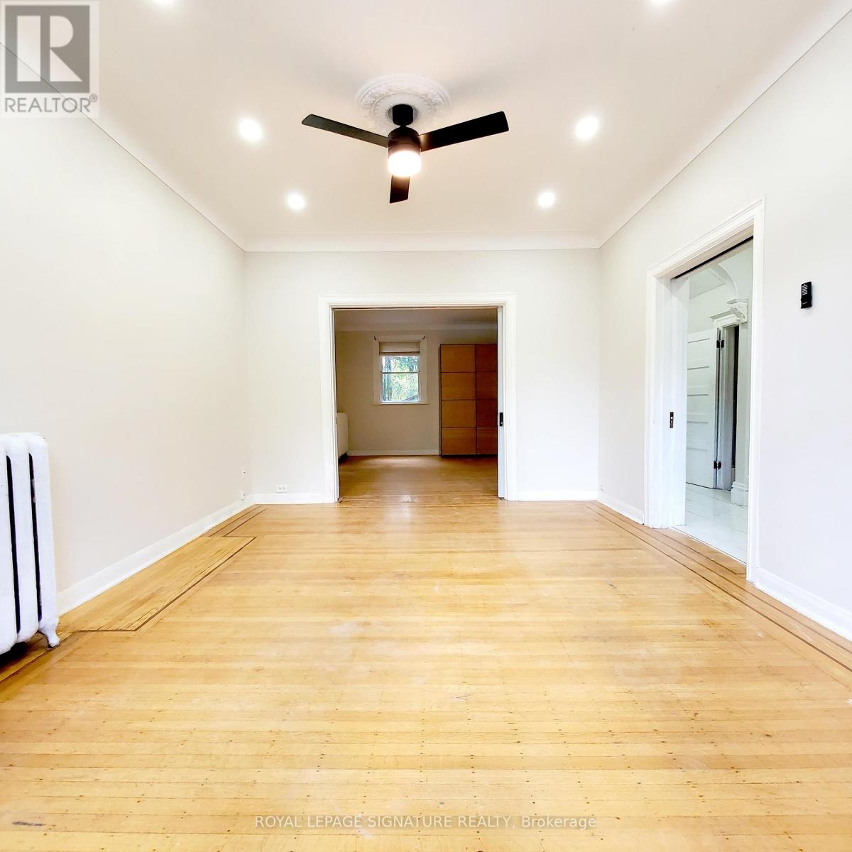 A room with a ceiling fan and wooden flooring.