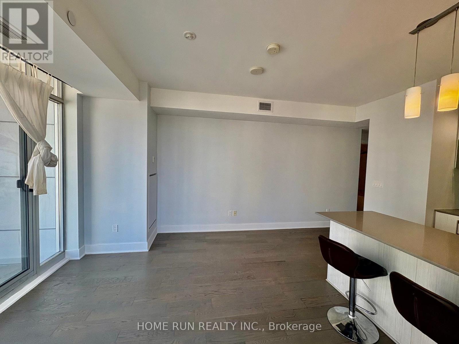 A spacious room with a bar area and a window with curtains.