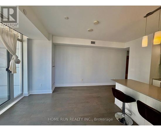 A spacious room with a bar area and a window with curtains.