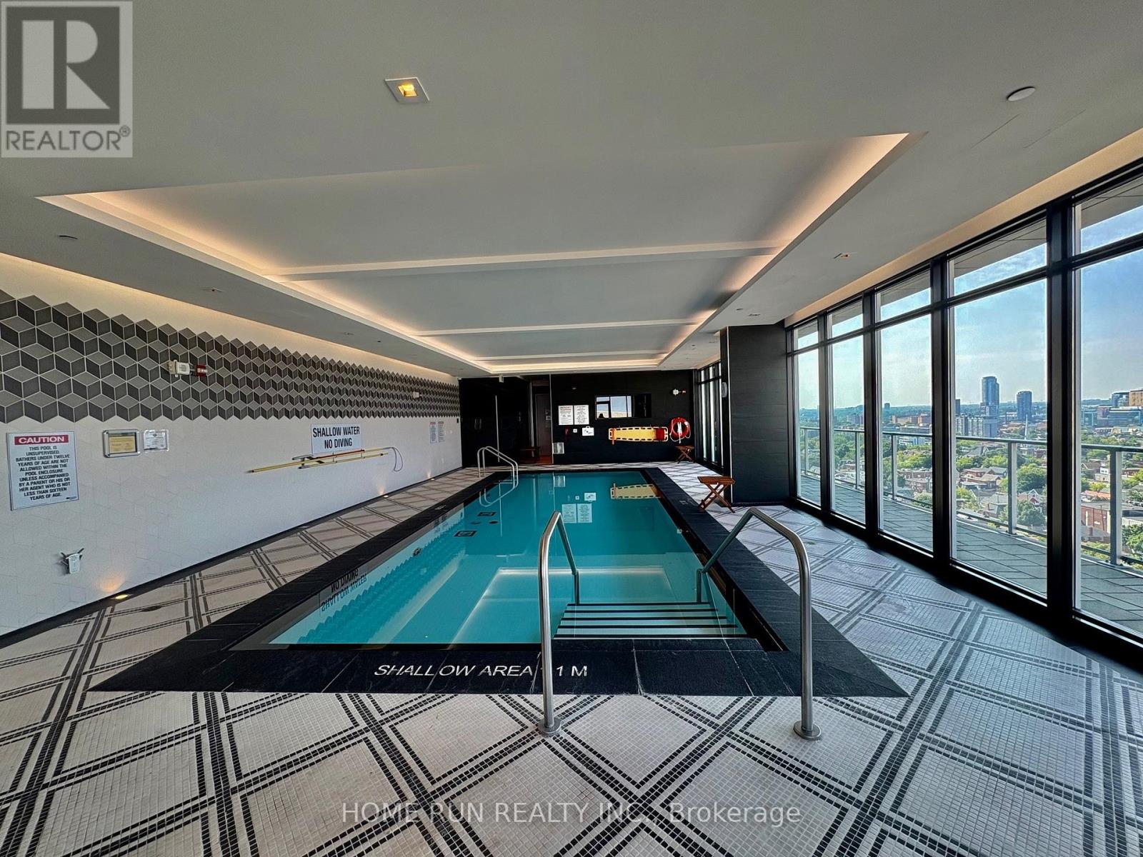 A swimming pool in a room with a tiled floor and a wall of windows.