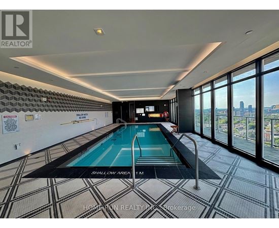 A swimming pool in a room with a tiled floor and a wall of windows.