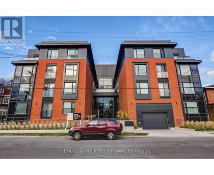 A red car is parked in front of a modern two-story building.