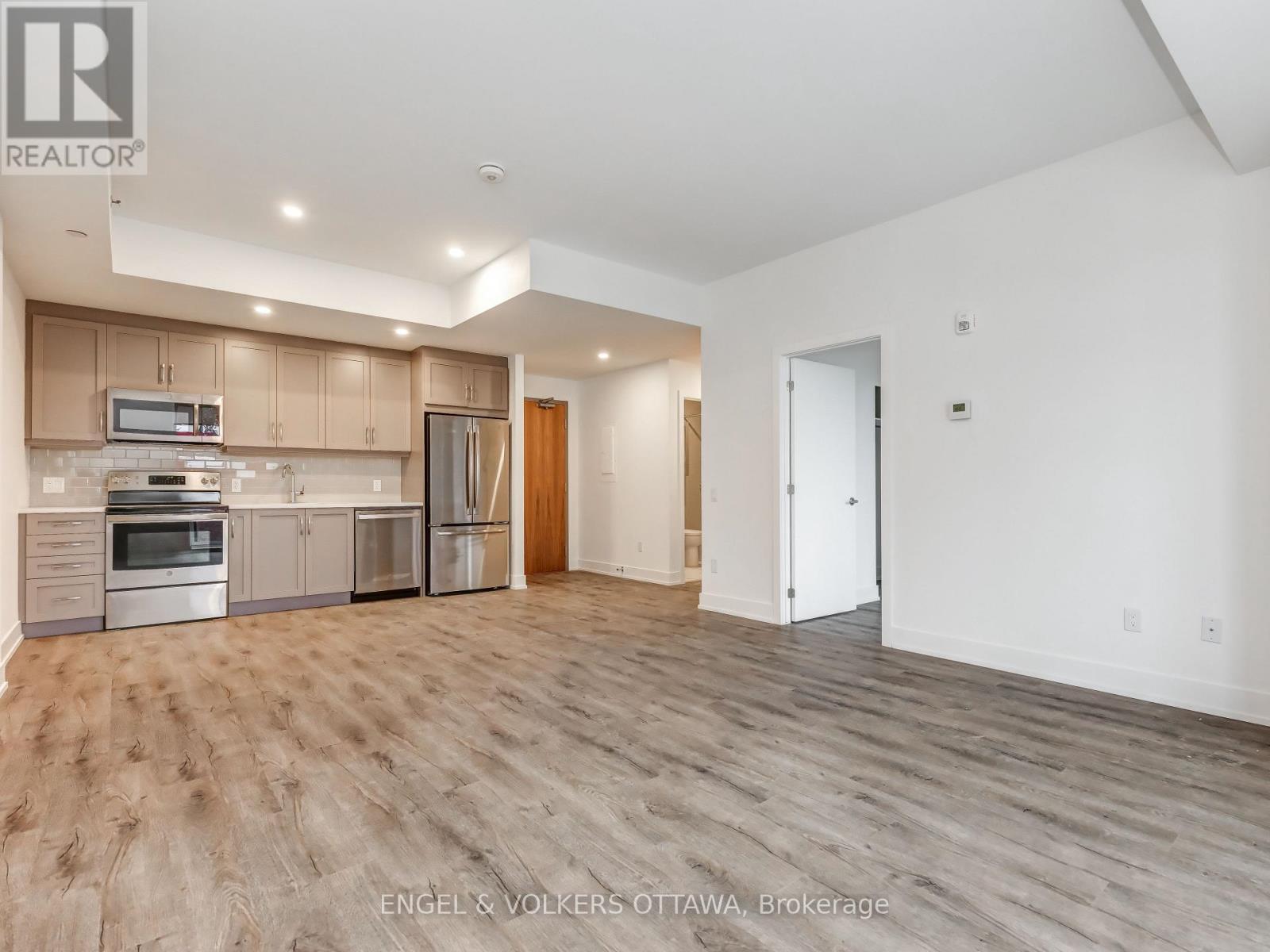 A spacious kitchen with wooden floors and a refrigerator, oven, and microwave.
