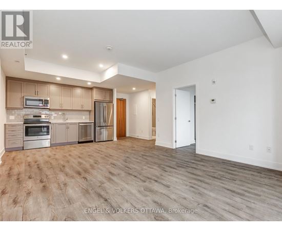 A spacious kitchen with wooden floors and a refrigerator, oven, and microwave.