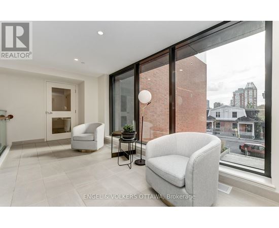 A living room with a grey couch and a glass table with a lamp on it.