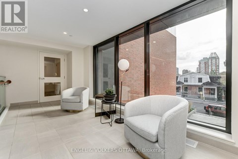 A living room with a grey couch and a glass table with a lamp on it.