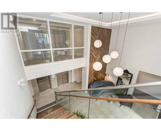 A modern interior space with a staircase and hanging lights.