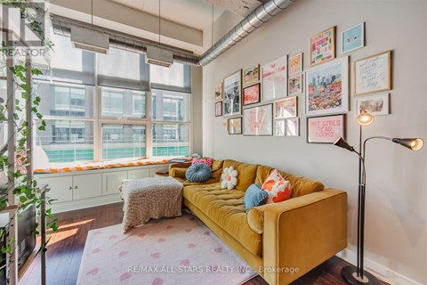 A living room with a yellow couch and pictures on the wall.