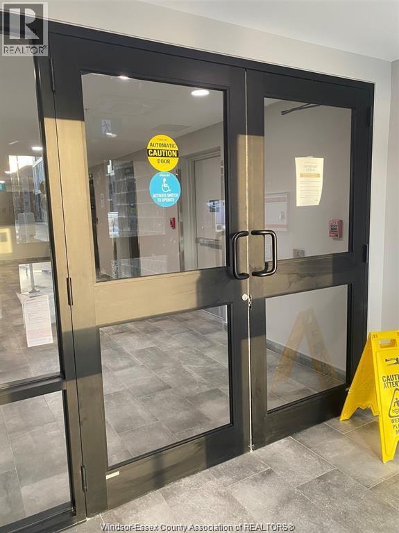 A glass door with a yellow caution sign in front of it.