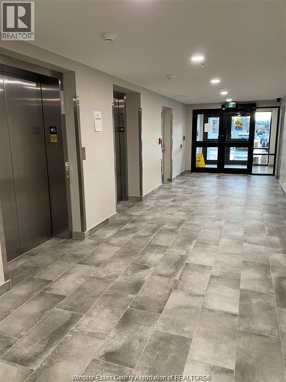 A hallway with a tiled floor and two elevators.