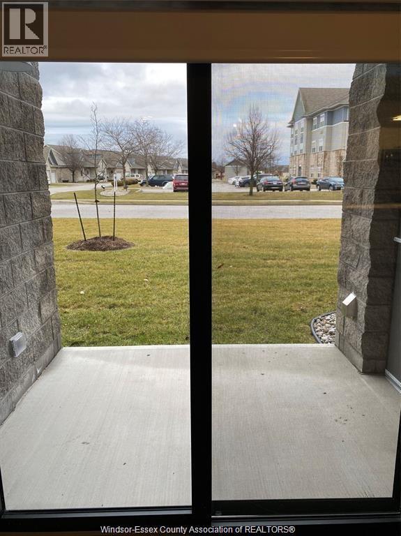 A view from a window looking out to a grassy area and a building.