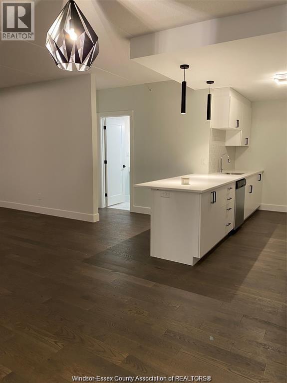 A kitchen with white cabinets and a wooden floor.