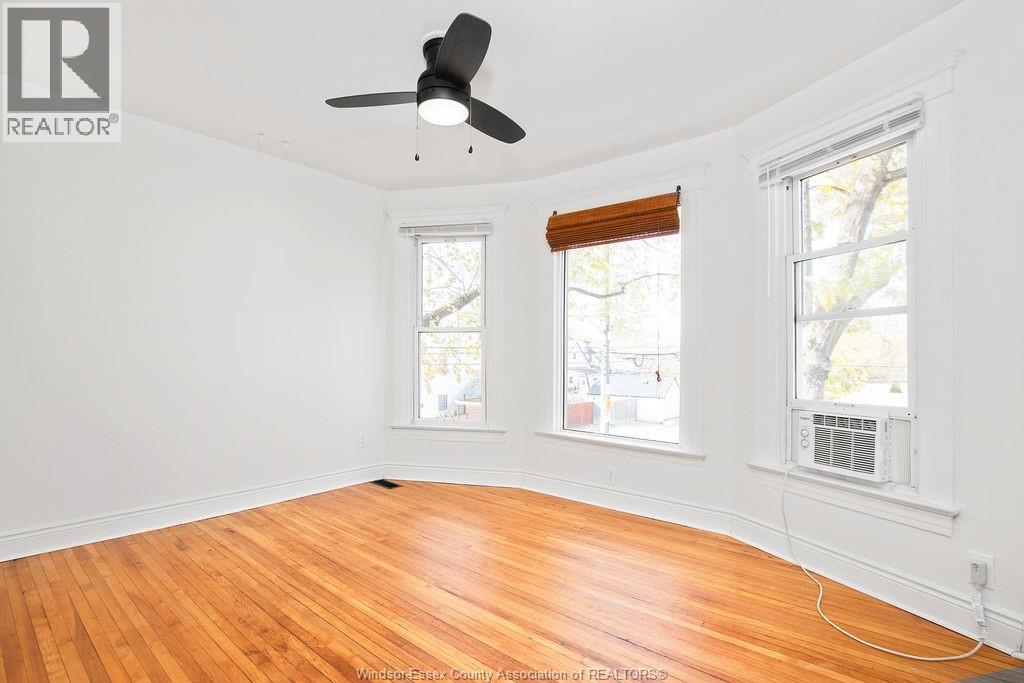 A room with a ceiling fan and two windows.