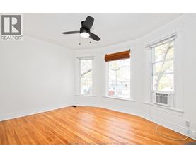 A room with a ceiling fan and two windows.