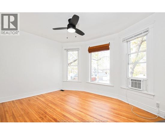 A room with a ceiling fan and two windows.
