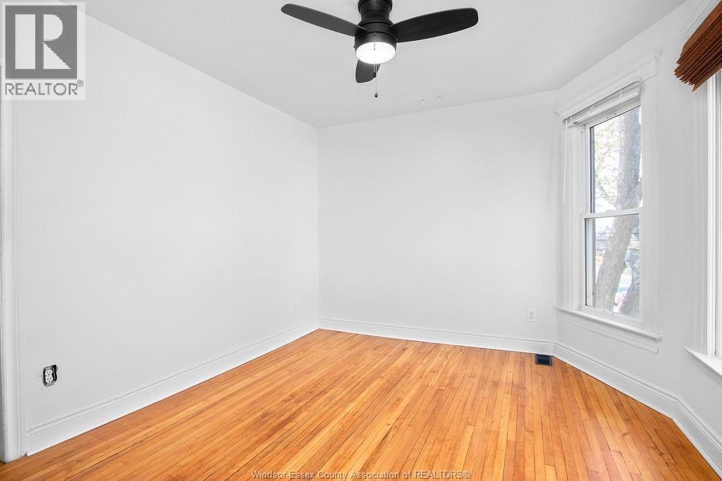 A room with a ceiling fan and hardwood floors.