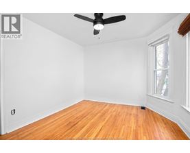 A room with a ceiling fan and hardwood floors.