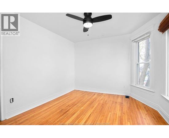 A room with a ceiling fan and hardwood floors.