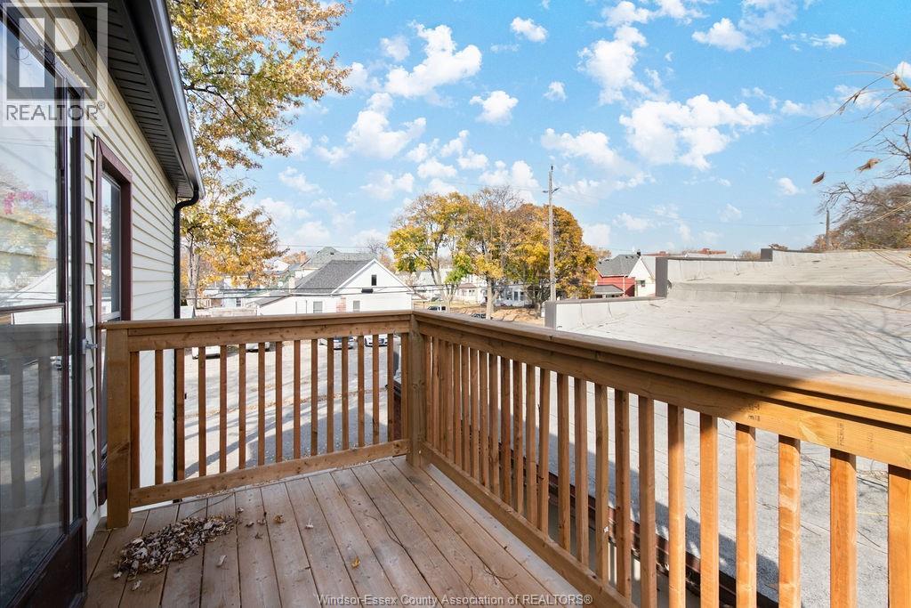 A wooden deck overlooks a street with houses and trees.