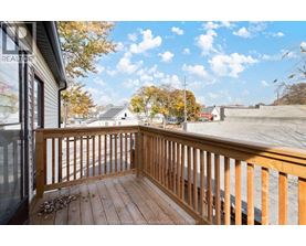 A wooden deck overlooks a street with houses and trees.