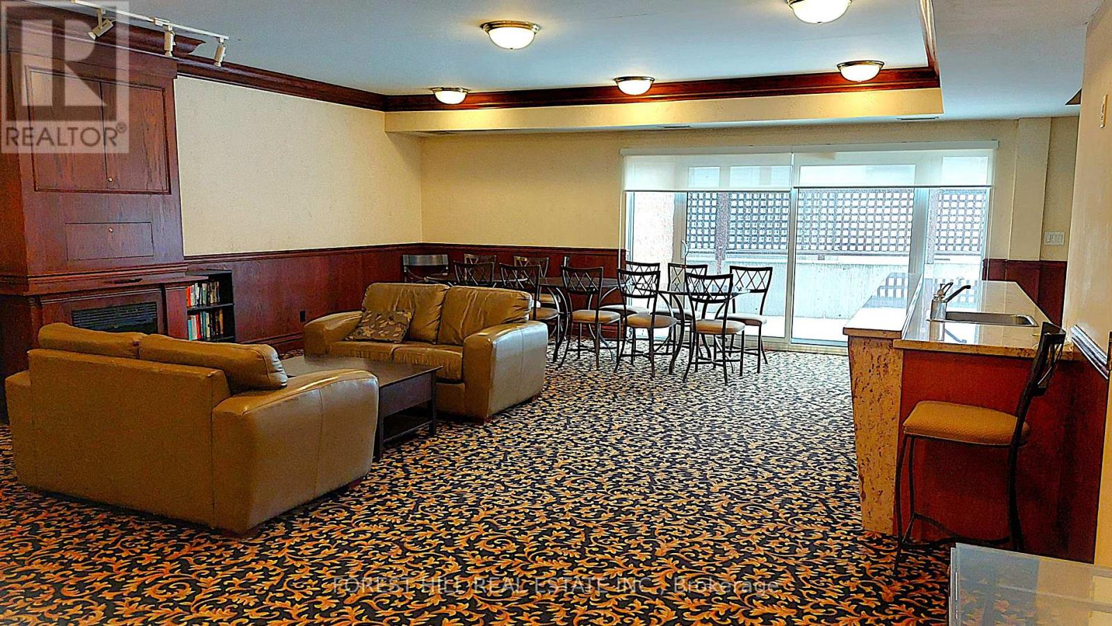 A living room with a brown leather couch and a patterned carpet.