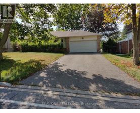 A driveway leads to a garage with a sign that says "REAL ONE REALTY INC., Brokerage.".