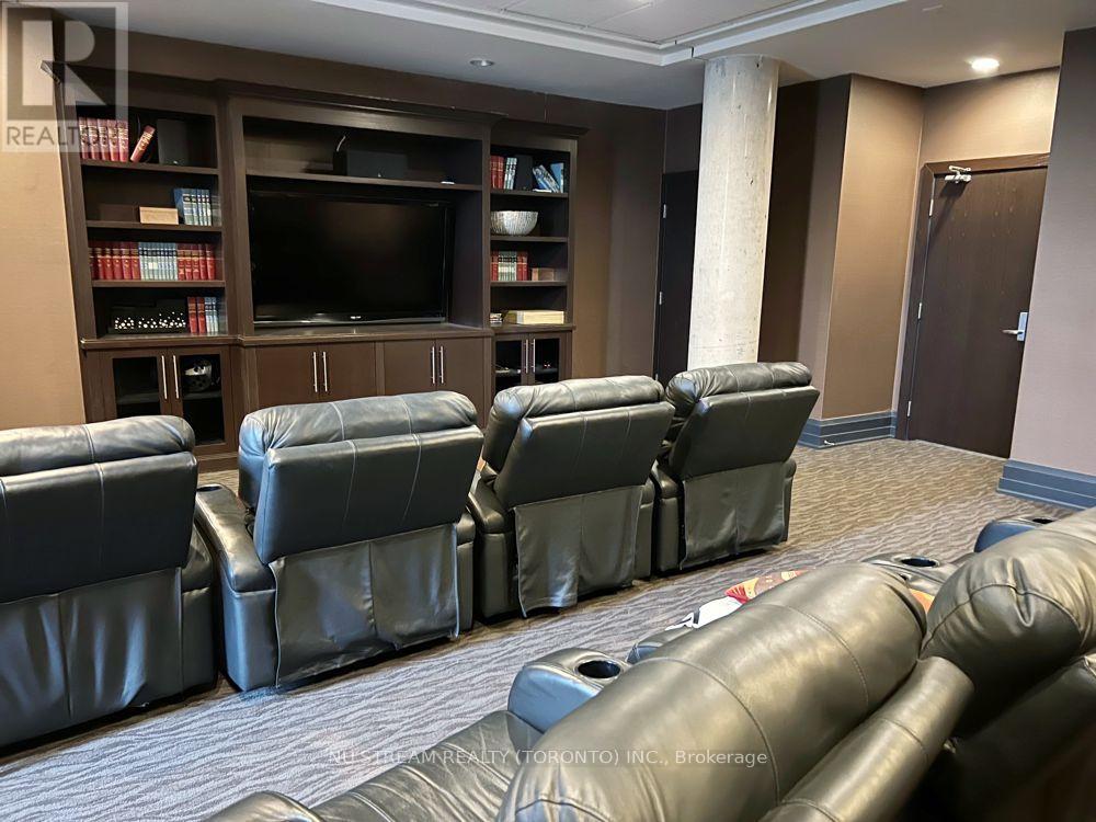 A living room with a row of black leather chairs facing a television.